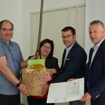 Vertreter von Rödlitz freuen sich über den Sieg im Dorfwettbewerb und erhalten einen Baum und eine Urkunde vom Beigeordneten des Landkreises Zwickau überreicht
