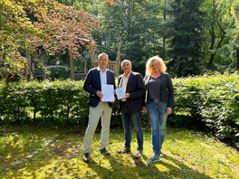 Auf diesem Spielplatz soll eine barrierefreie Picknick-Ecke entstehen. Landrat Carsten Michaelis (links im Bild) brachte den Zuwendungsbescheid persönlich vorbei.